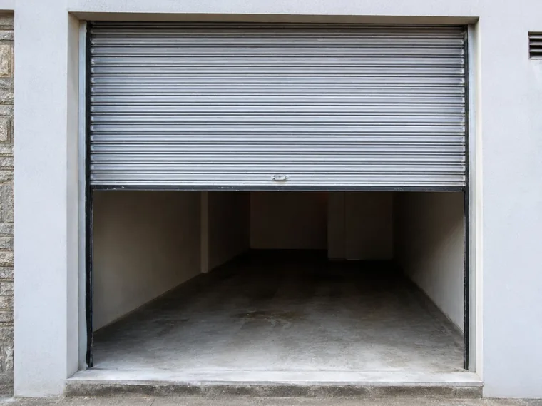 Porta de aço de enrolar manual entreaberta em garagem
