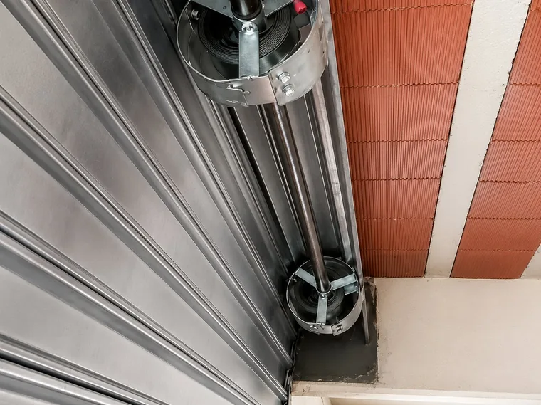 Molas e tambores tensores no topo de uma porta de aço